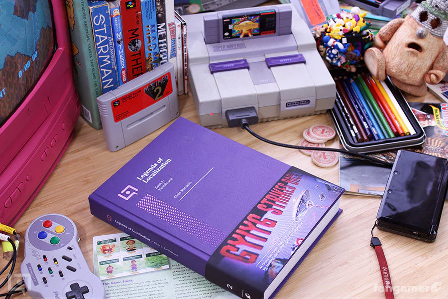 Purple book titled 'The Legend of Zelda' on a desk with a SNES console and colorful items.