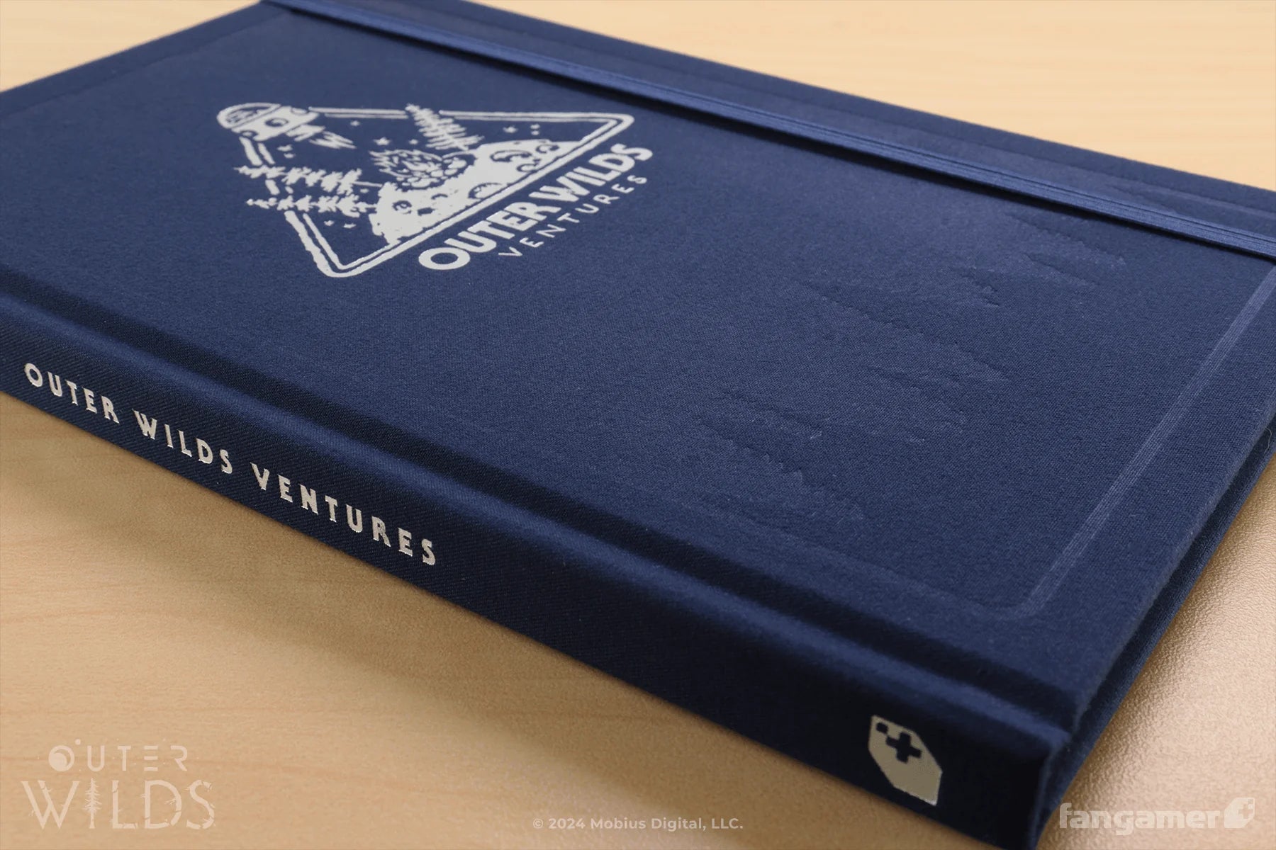 Blue book titled 'Outer Wilds Ventures' with a logo on a beige background