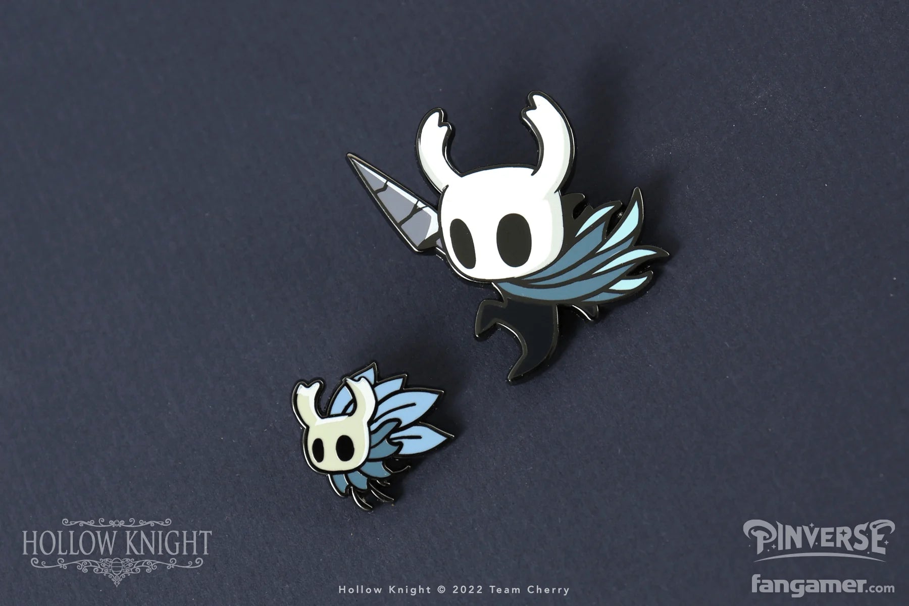 Two enamel pins of Hollow Knight characters on a dark background with branding visible.