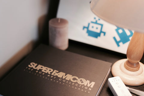 Super Famicom book sitting on bedside table with lamp and candle